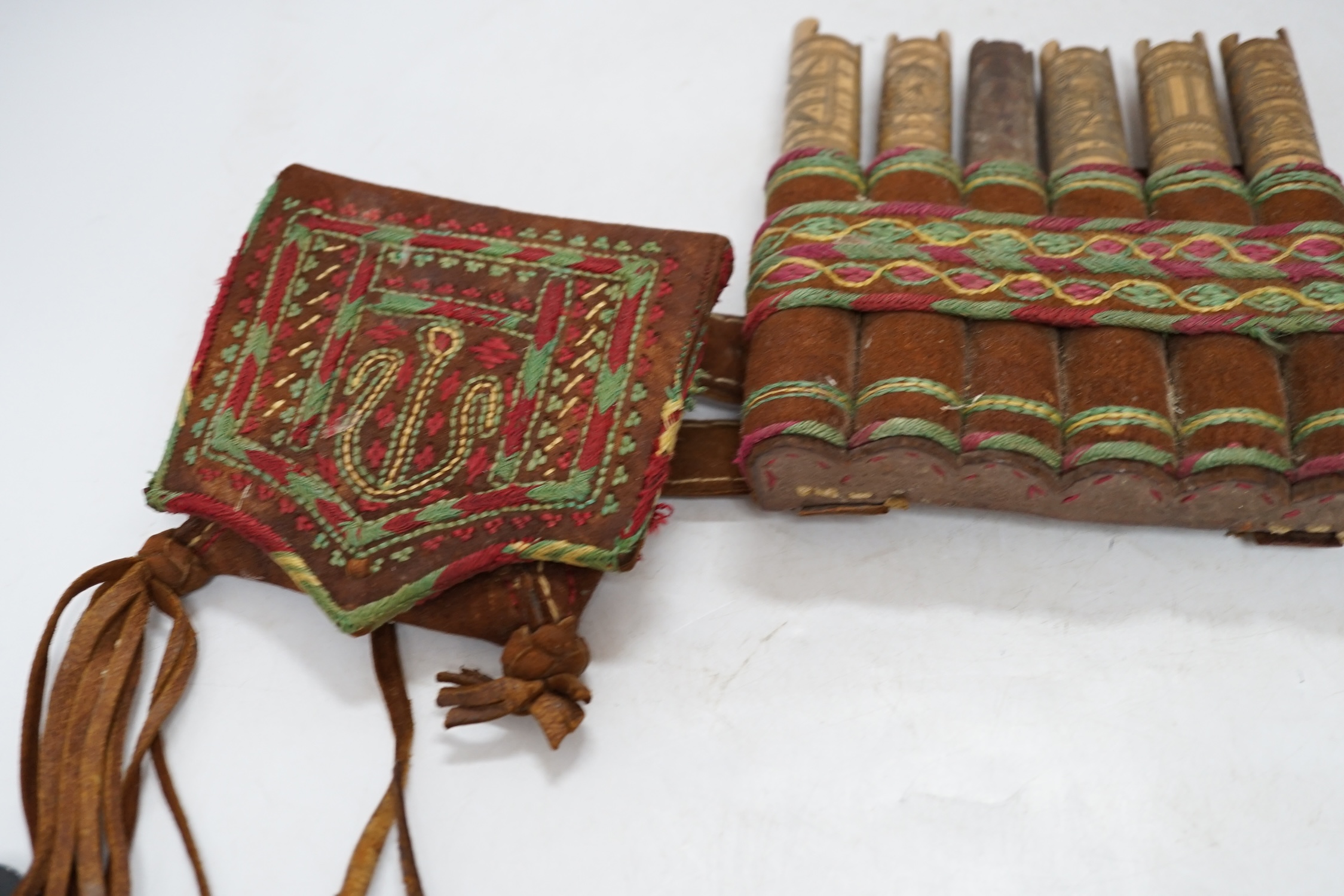 A 19th century Armenian gazyr belt, with decorative silk embroidery on suede and carved bamboo shot and gunpowder containers, 68cm long. Condition - slightly worn from use